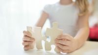 A young girl holds two puzzle pieces.