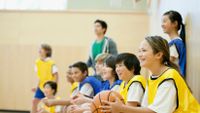 Students sitting on basketball court smiling