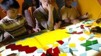 Kids and adult sitting around a table with geometric puzzle pieces