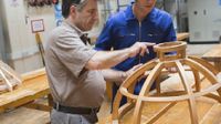 Man pointing out something to boy in wood shop