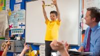 Boy standing in front of the class holding a big key