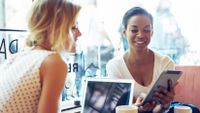 Two female teachers consider the merits of apps on their tablets.