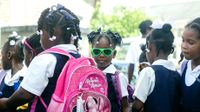 Group of students, many wearing backpacks, and one girl wearing neon green sunglasses