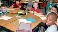 A classroom full of children are sitting at their desks.