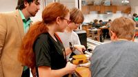 Teacher and students gathered around looking down at a project