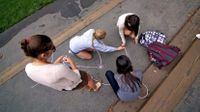 Teacher watching young students working a math problem with sidewalk chalk