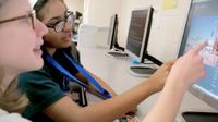 Photo of students pointing at computer screen