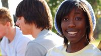 Girl sitting with two boys smiling at the camera