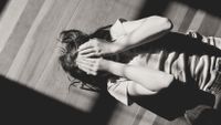 Girl lying on back with hands over face