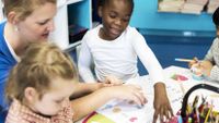 Young children work on literacy exercises with their teacher.
