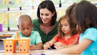 Female educator helping a group of young children with their work.