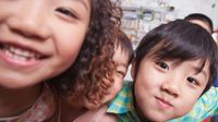 Close up of three children smiling at the camera