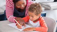 Teacher helping a little boy with his work