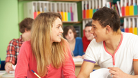 Two teenagers smile at each other in support.