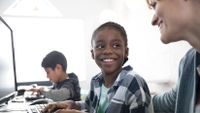 A boy looks up at his teacher with a smile.
