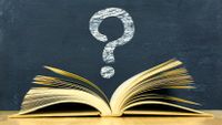 Image of an open book under a question mark written in chalk on a blackboard