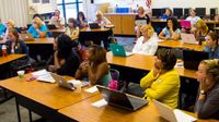 A classroom full of teachers listening with laptops open