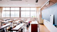 Traditional classroom with desks in rows facing teacher's desk in front of the blackboard