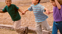 A photo of elementary school children holding hands and laughing.