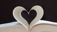 Photo of an open book with two pages curled to resemble a heart