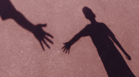 Shadow of two people reaching out their hands to each other