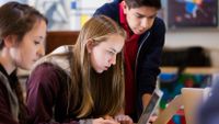 High school students discuss something on a computer screen in front of them.