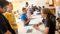 A student explains his poster to two of his peers.