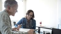 An instructional coach and a teacher discuss some paperwork.