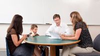 Mom, dad, and boy speaking with teacher around a table