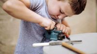 Young boy determined to make something fit using a vice