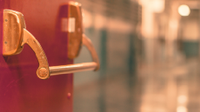 Photo of a door opening to an empty school hallway