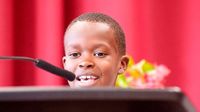 Young boy speaking, almost hidden by the podium he's standing behind