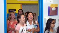 Young girls are walking into a classroom with smiles on their faces.