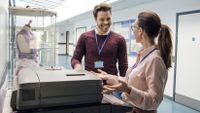 Two adults stand by a copy machine, smiling at each other.
