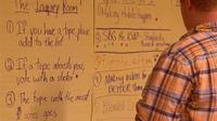 A photo of a teacher at a whiteboard in a strategy session.