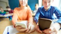 Two students look at their phones in class.