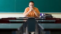 Man sitting at desk in an empty classroom