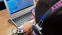 Girl wearing headphones working on a laptop