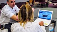 Man and woman using laptop speaking at a table