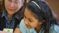 A photo of a female teacher working with an elementary-school girl.