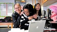 Three girls smiling behind a laptop