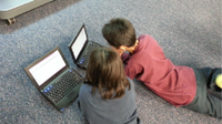 A photo of 2 elementary-school boys doing research on laptops.
