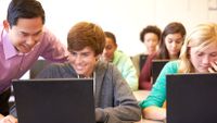 A teacher and student discuss text on the student’s laptop screen.
