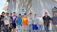 11 boys standing in front of a two-story house they have been renovating