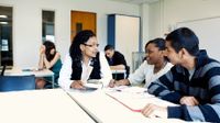 Teacher speaking with two older students at a table