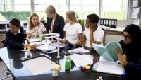 A teacher and students gather around a table in their classroom.