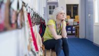 A teacher takes a break in the hall outside of her classroom.
