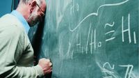 Man with his forehead and fist against a blackboard