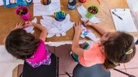 Two young girls doing a project with scissors and pens