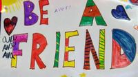 A poster pinned on the wall drawn by students that says "Be A Friend"